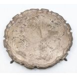 A George V large silver salver, pie crust rim raised on four trefid feet, hallmarked by Goldsmiths &