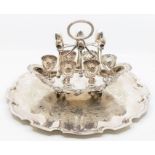 An Edwardian EPNS six piece egg cruet stand, on navette shaped base with ornate border, central oval