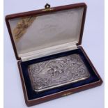 A Siamese white metal cigarette case embossed to the front with figure among leafage scroll and with