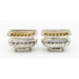 A pair of Georgian style oblong silver salts, gadrooned bodies on four ball, gilt interiors,