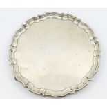 A Georgian style silver pie crust rim salver on three scroll feet, hallmarked by Frank Cobb Ltd,