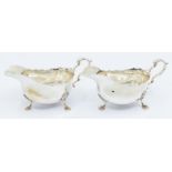 A pair of Georgian style plain silver oval sauceboats, wavy rim on three shell feet, hallmarked by