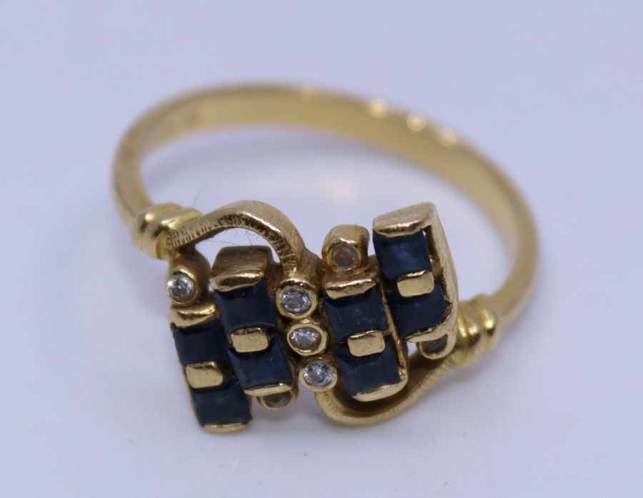 An 18ct yellow gold, diamond and sapphire cross-over ring, set eight square cut sapphires and