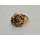 An Italian 18ct. gold and ruby ring, having pierced head fashioned twin flowers, the centres of each