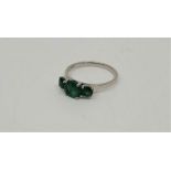 A 18ct. white gold three stone emerald ring, set three graduated round cut emeralds (centre stone