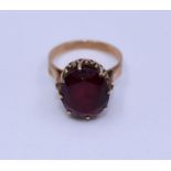 A precious yellow metal and synthetic ruby ring, claw set large central oval mixed cut synthetic