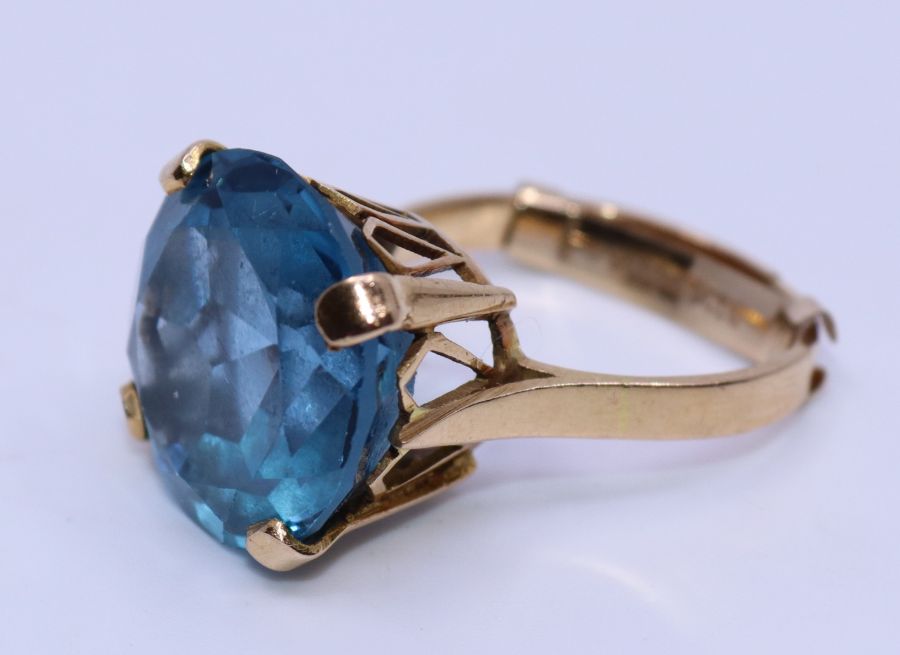 An 18ct. yellow gold blue topaz cocktail ring, four claw set round mixed cut brilliant blue topaz,