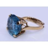 An 18ct. yellow gold blue topaz cocktail ring, four claw set round mixed cut brilliant blue topaz,