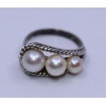 A white metal and cultured pearl ring, set row of three graduated cultured pearls within filigree