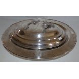 A large silver platted platter with a greek key border raised on 4 dragon head feet and a cover with