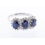 A sapphire and diamond ring 18ct gold ring, comprising three oval sapphires each claw set within a