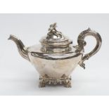 A Victorian silver teapot, plain ogee shaped engraved with a crest within wreath on four scroll