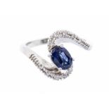 A sapphire and white topaz 18ct white gold ring, the centre with a claw set oval sapphire, approx