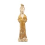 A Tang Dynasty pottery figure of a female attendant, her hands concealed by her flowing robes, her