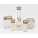 A collection of six early 20th Century facet cut glass toilet bottles with silver covers, various