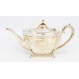 A George V shaped silver teapot, the body engraved with Neo-Classical decoration, on four scroll
