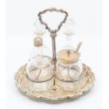 An Edwardian cruet stand, the base with raised border, on bun feet, with wire work frame and