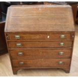 A George III large oak bureau with four lower drawers and brass swing handles
