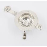 An early 20th Century Swedish silver tea strainer and stand, the body with floral motifs, the body