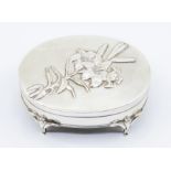 An Edwardian silver plain oval dressing table / ring box, the cover chased with a Lily, on four Lily