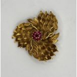 AN 18k stylized floral brooch with ruby cluster to the centre, stamped 750, CFF. Approx gross weight