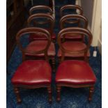 A set of six balloon back dining chairs, with red leather close nailed upholstery and on turned