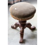 A Victorian walnut revolving tripod piano stool with stuffed seat