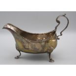 An early 19th silver sauce boat, flying scroll handle and punched rim, on three shell capped hoof