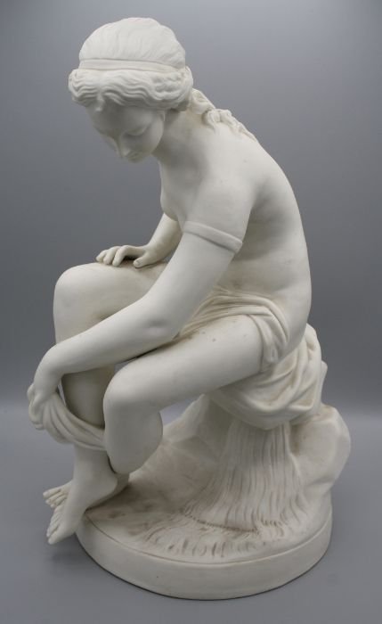 A 19th century English parian figure of a female nude, seated upon a rock, drying with a robe,