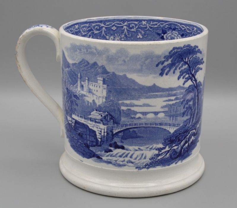 A mid 19th century English pottery mug, with flat strap handle and ogee foot, printed underglaze