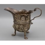 A mid 18th century Irish silver cream jug, helmet shape with Rococo chasing arount vacant cartouche,