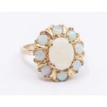 An opal and 9ct gold cluster ring, set with an oval opal within a border of round opals, size M,