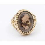 A 9ct gold smoky quartz ring comprising an oval cut quartz, to a textured open work mount, size L,