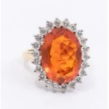 A fire opal and diamond 18ct gold cluster ring, set with an oval opal approx 11 x 15mm, within a