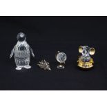 Four Swarovski figures including baby elephant, hedgehog, globe and a penguin, in boxes