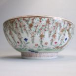 A large Late 19th century polychrome Chinese bowl painted with cascading branches and flowers from