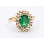 An emerald  and diamond 18ct gold cluster ring, comprising a claw set central oval cut emerald