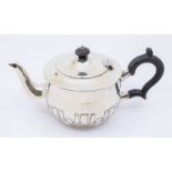 An Arts & Crafts silver planished teapot, strapwork decorative panel to underside, ebony handle