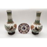 A pair of early 20th Century Chinese porcelain vases on wooden stands, with bird and foliage detail,