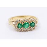 An emerald and diamond 18ct gold cluster ring, comprising three round cut claw set emeralds,