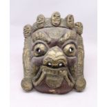 A carved wooden Far Eastern wall hanging face mask