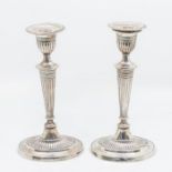 A pair of George V silver Neo-Classical style candlesticks, beaded detachable drip pans above urn
