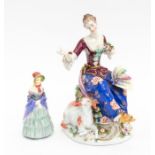 A Dresden 18th Century style porcelain figure of a seated Lady with hat on knee and sheep beside,