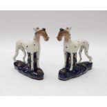 A pair of 19th Century style Staffordshire figures of spotted hounds, cobalt blue base, each holding