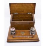 An early 20th Century oak desk stand with two glass inkwells either side of penwell