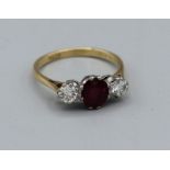 An 18ct stamped yellow metal dress ring featuring a central ruby of 8 x 5mm approx and two diamonds,