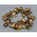 A 9ct gold charm bracelet with nineteen charms (including articulated charms) and a padlock clasp,