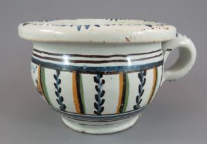 An eighteenth century tin glazed earthenware small chamber pot, c. 1760. It is decorated with a
