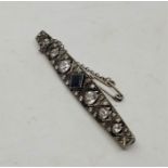 An Art Deco precious white metal, sapphire, and diamond brooch, set central square cut blue sapphire