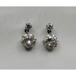 A pair of precious white metal diamond drop earrings, each claw set round brilliant cut diamond